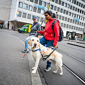 Führhundehalterin überquert mit ihrem Blindenhund eine Strasse.