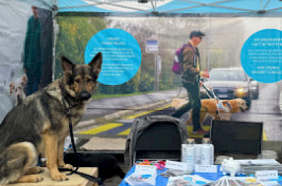 Beschriftetes Zelt mit Hund und Merch-Artikeln im Vordergrund