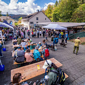 Gäste sitzen gemeinsam an Festtischen im Freien.